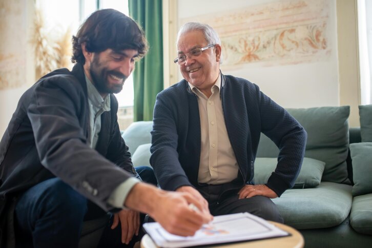 Consulente assicurativo che illustra una polizza a un cliente seduto alla scrivania